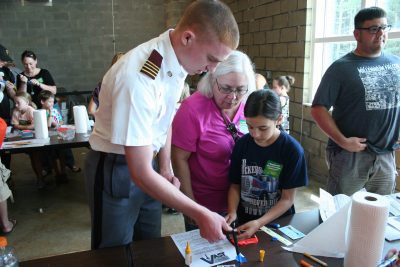 Fishburne Military School cadet assists a young student in building a rocket